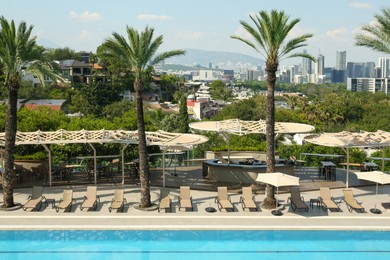 Photo of Sunbeds and palm trees near outdoor swimming pool