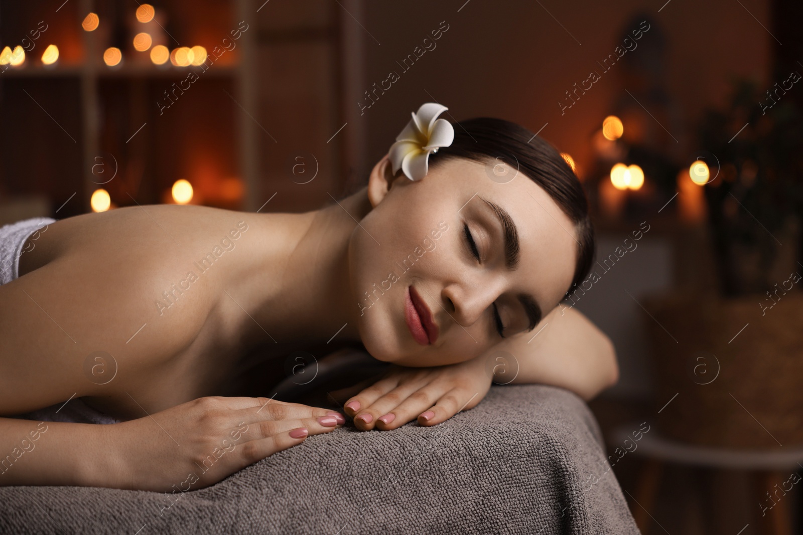 Photo of Spa therapy. Beautiful young woman lying on massage table in salon