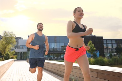 Healthy lifestyle. Happy couple running outdoors on sunny day, low angle view