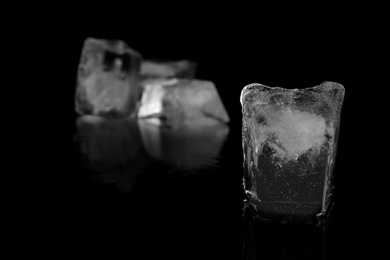 Photo of Transparent ice cube on black mirror surface