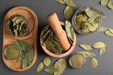 Photo of Whole and ground bay leaves on grey wooden table, flat lay