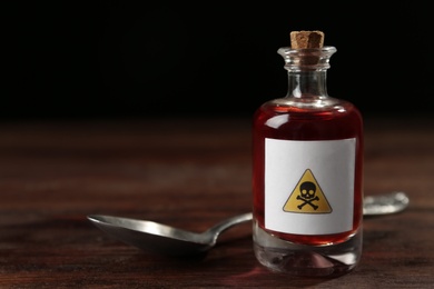 Photo of Bottle with poison and spoon on wooden table. Space for text