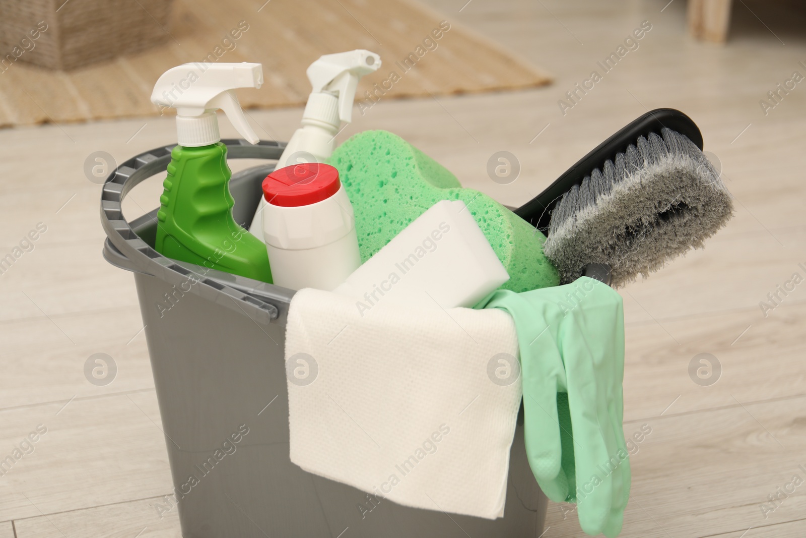 Photo of Different cleaning products in bucket on floor indoors