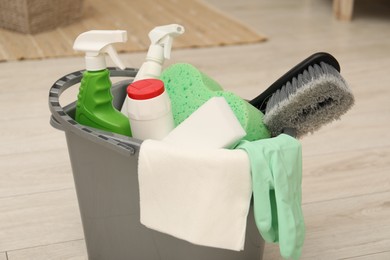 Photo of Different cleaning products in bucket on floor indoors