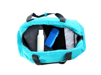 Photo of Sport bag with deodorants and clothes on white background, top view