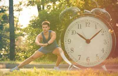 Image of Workout time. Double exposure of man doing exercise on sunny morning in park and alarm clock, color toned