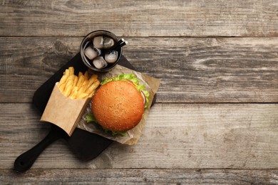 French fries, tasty burger and drink on wooden table, top view. Space for text