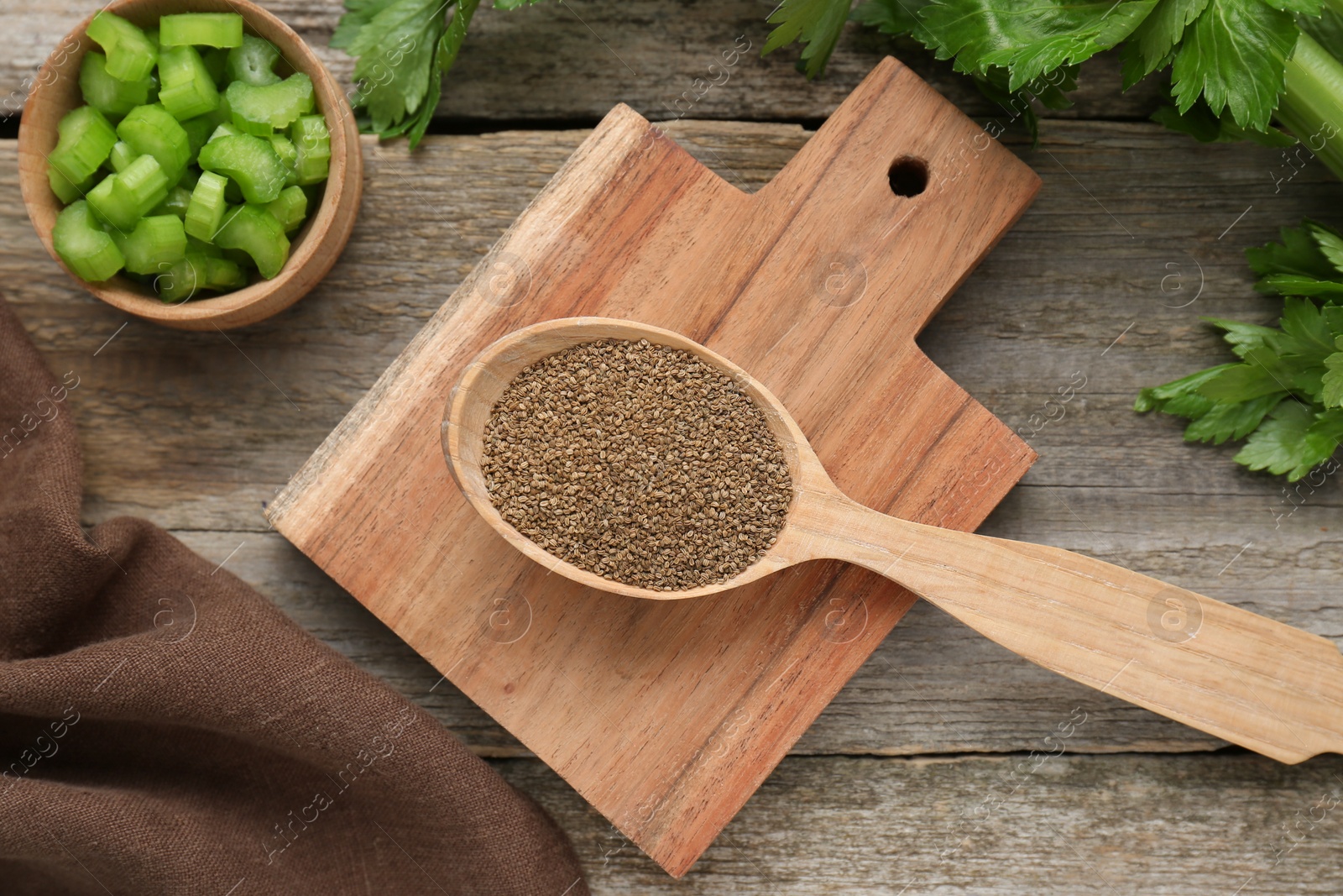 Photo of Spoon of celery seeds and fresh plant on wooden table, flat lay