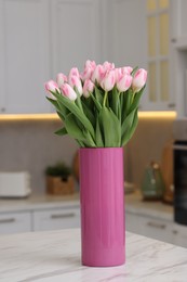 Photo of Beautiful bouquet of fresh pink tulips on table in kitchen