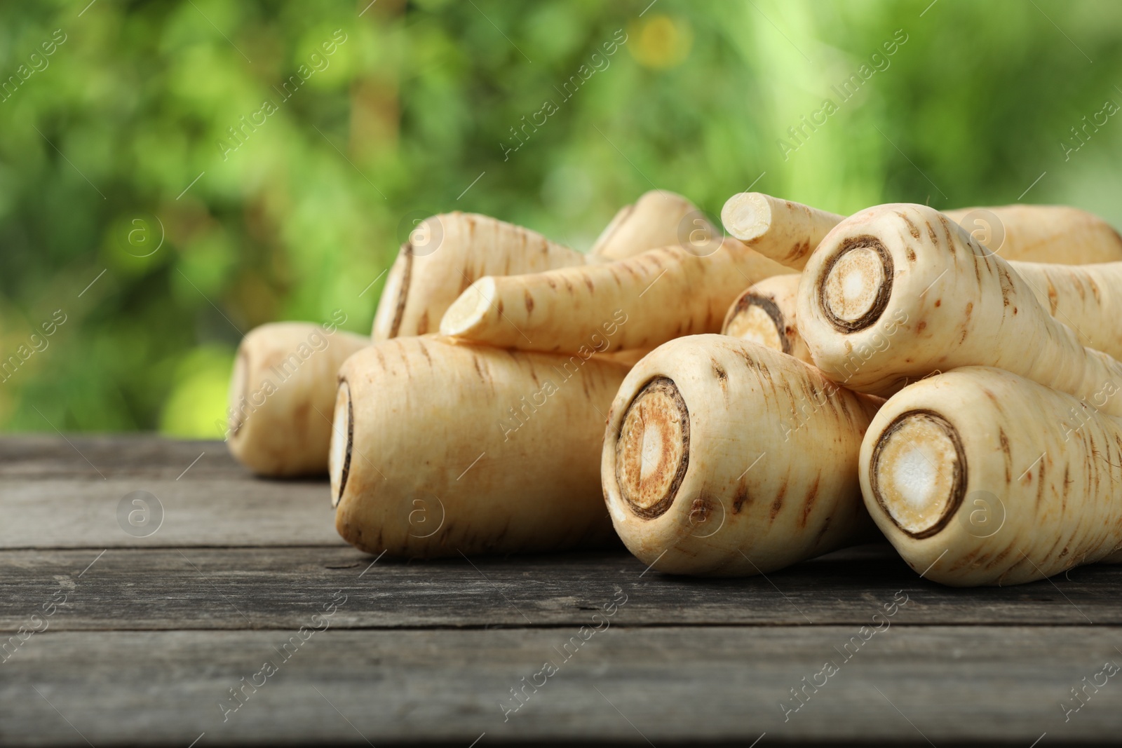 Photo of Delicious fresh ripe parsnips on wooden table outdoors, space for text