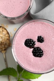 Photo of Glasses of blackberry smoothie and oatmeal on white table, flat lay