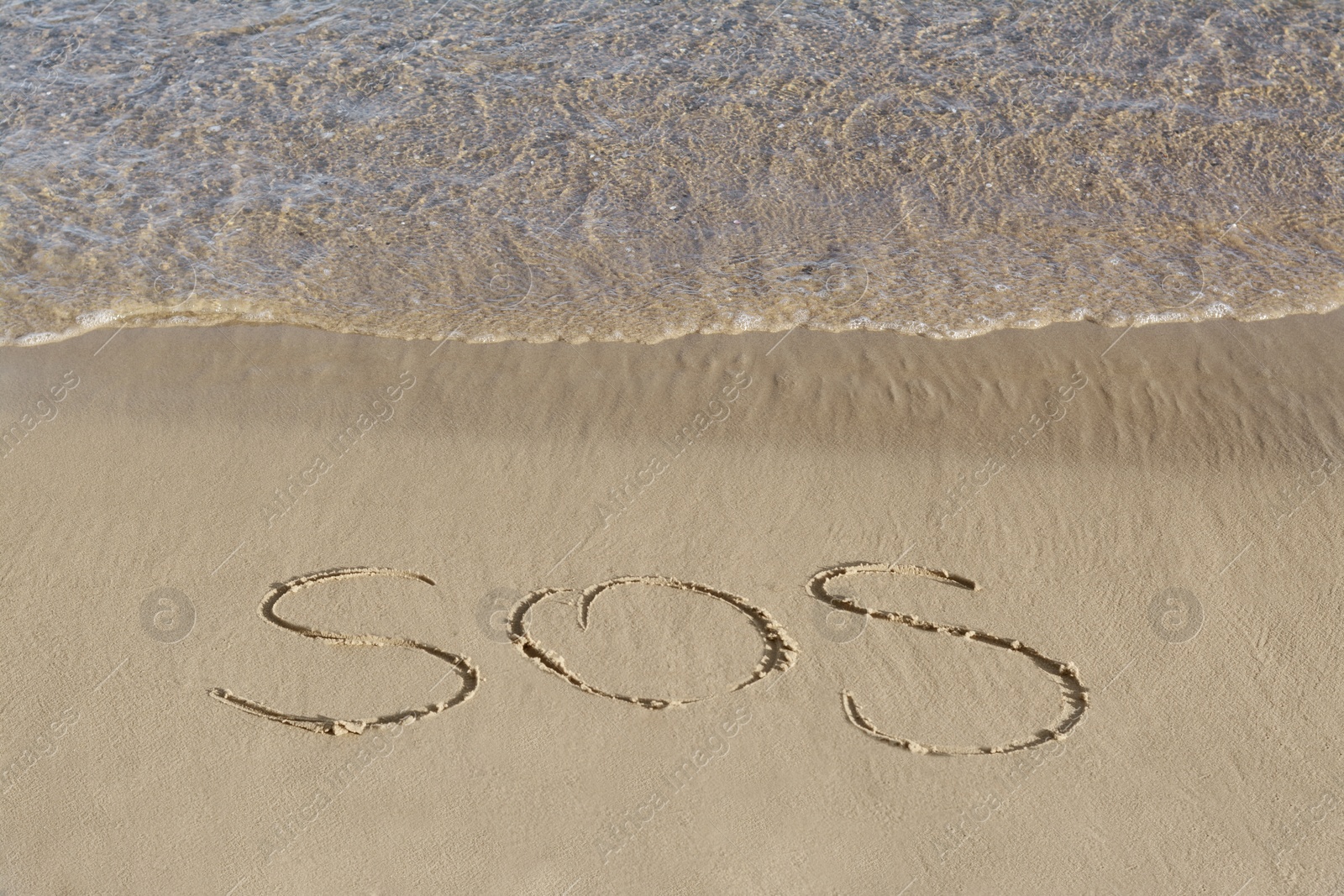 Photo of SOS message written on sand near sea