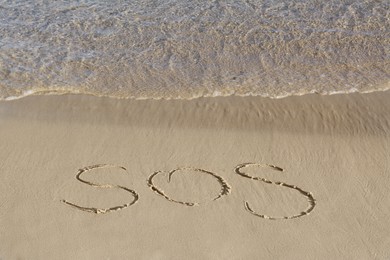 Photo of SOS message written on sand near sea