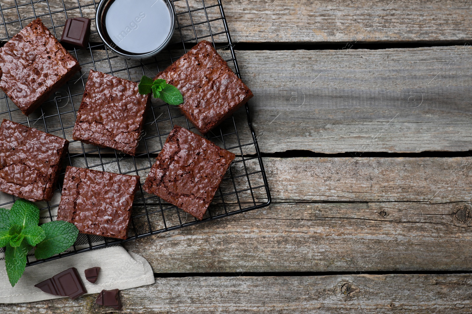 Photo of Cooling rack with delicious chocolate brownies and fresh mint on wooden table, flat lay. Space for text