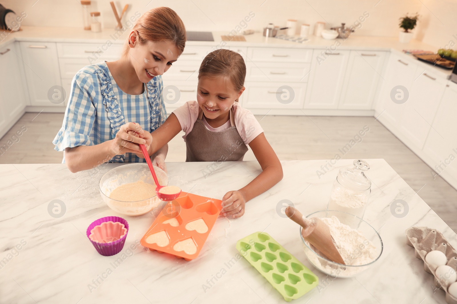 Photo of Mother and daughter making cupcakes together in kitchen