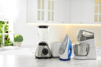 Photo of Set of modern home appliances on white marble table in kitchen