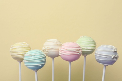 Sweet colorful cake pops on yellow background, space for text