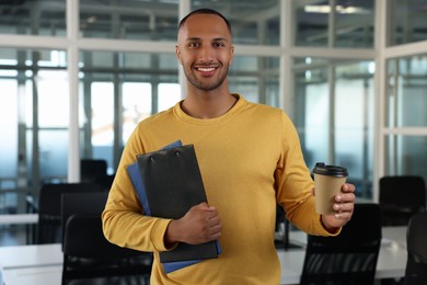 Photo of Happy man with clipboards and paper cup of drink in office