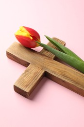 Photo of Easter - celebration of Jesus resurrection. Wooden cross and tulip on pink background, closeup