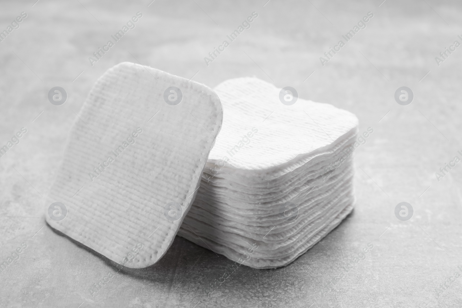 Photo of Stack of clean cotton pads on light grey table, closeup