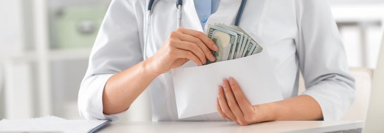 Image of Doctor with bribe at desk in clinic, closeup. Banner design