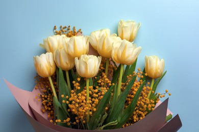 Bouquet with beautiful tulips and mimosa flowers on light grey background, top view