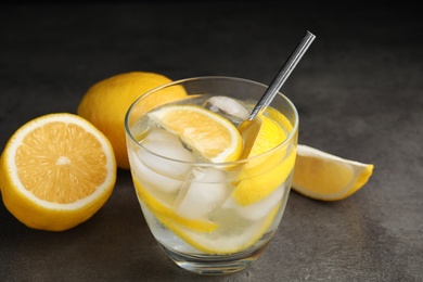 Soda water with lemon slices and ice cubes on grey table