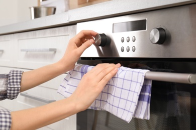 Young woman adjusting oven settings in kitchen, closeup