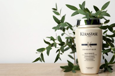 MYKOLAIV, UKRAINE - SEPTEMBER 07, 2021: Kerastase shampoo and green branches on wooden table. Space for text