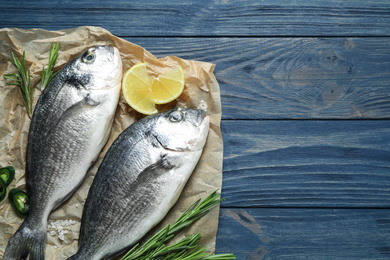 Photo of Raw dorada fish on blue wooden table, top view. Space for text