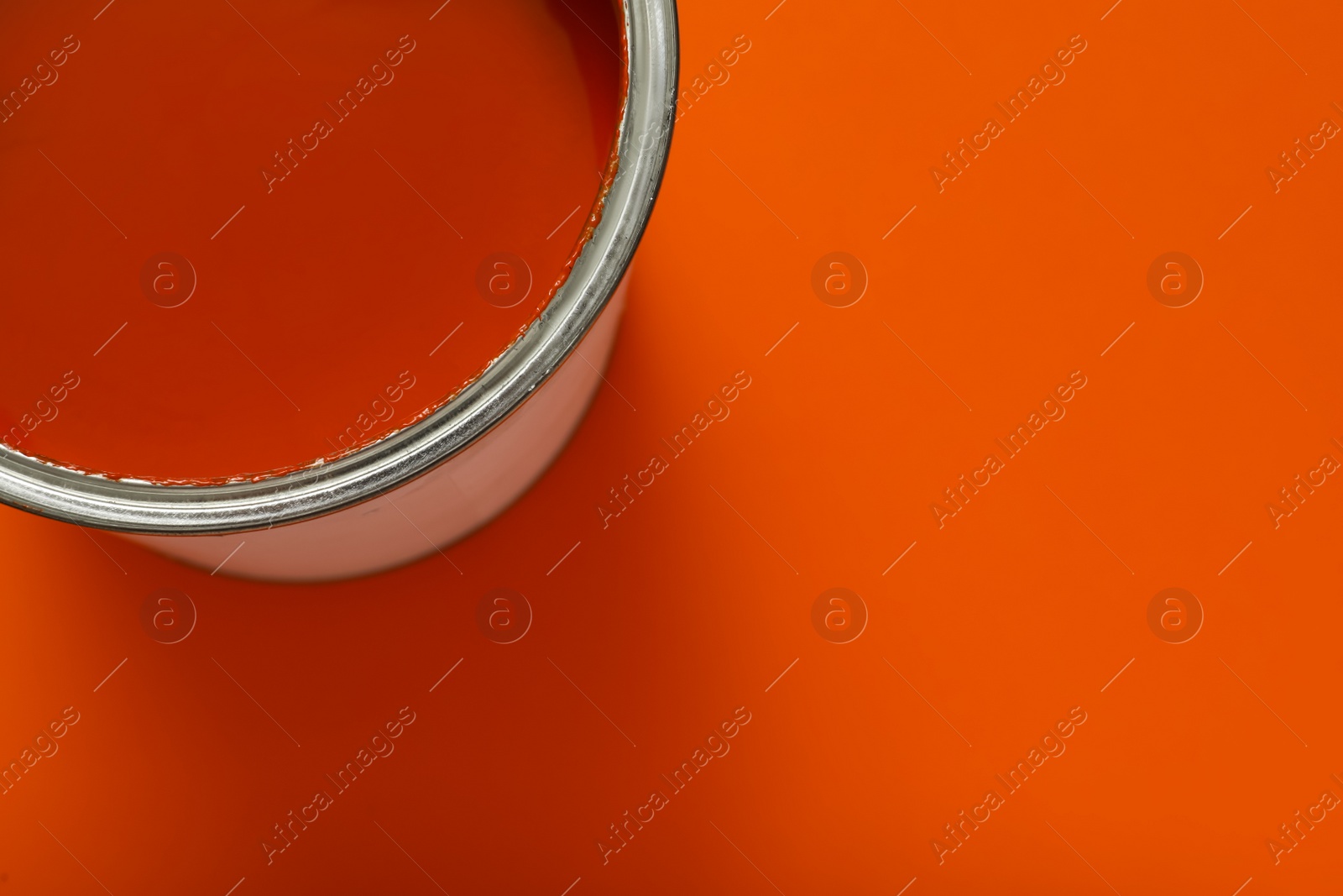 Photo of Can of orange paint on color background, top view. Space for text