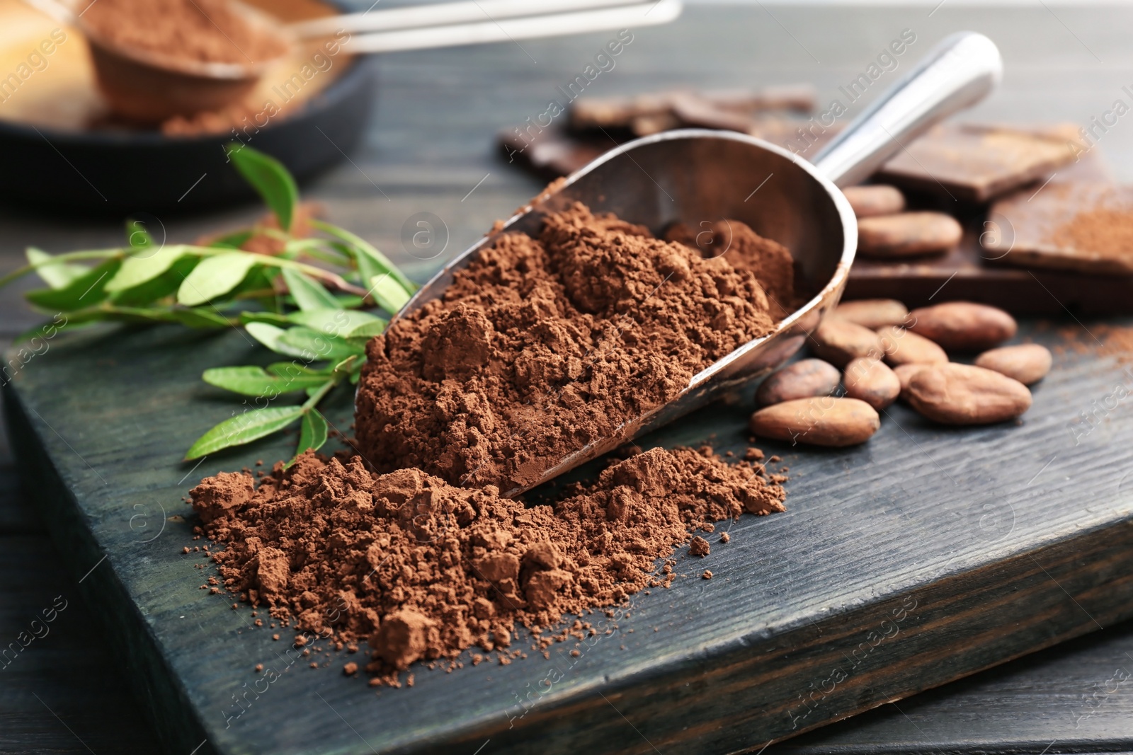 Photo of Scoop with cocoa powder on wooden board