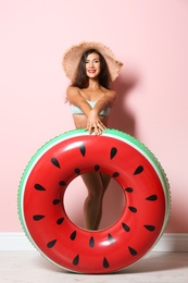 Beautiful young woman with inflatable ring near color wall