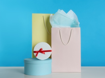 Photo of Gift bags and boxes on white table against light blue background