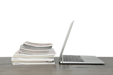 Photo of Stack of magazines and laptop on table near white wall