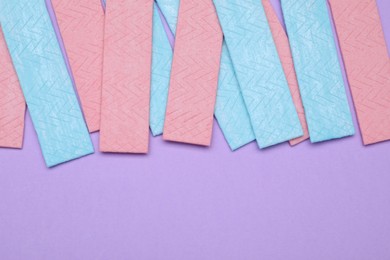 Photo of Many sticks of tasty chewing gum on violet background, flat lay. Space for text