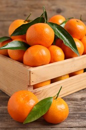 Photo of Delicious tangerines with leaves on wooden table