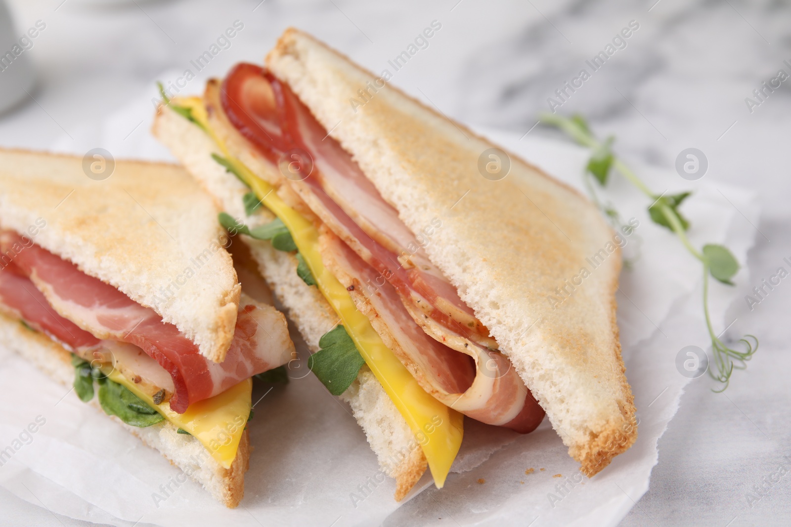 Photo of Delicious sandwiches with bacon on white table, closeup