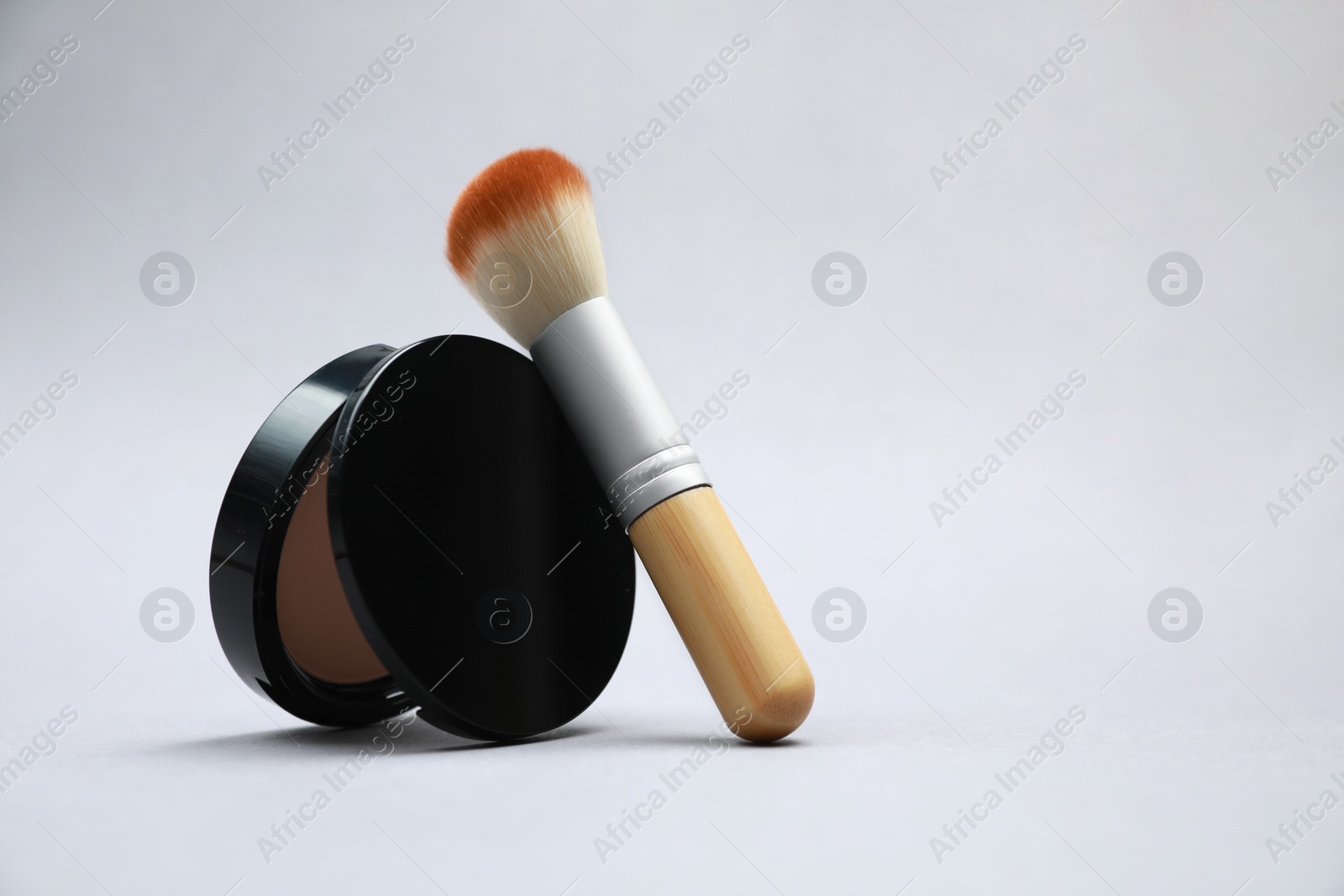 Photo of Face powder and brush on light grey background. Space for text