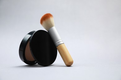 Photo of Face powder and brush on light grey background. Space for text