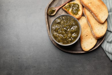 Photo of Toasts with delicious gooseberry jam on grey table, top view. Space for text