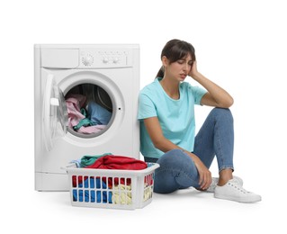 Photo of Unhappy woman near washing machine with laundry on white background