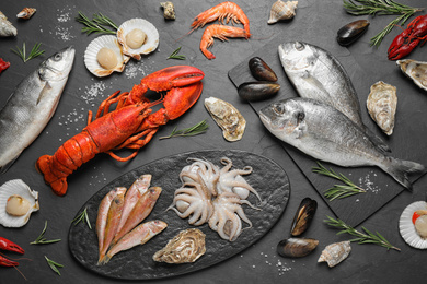 Fresh fish and different seafood on black table, flat lay