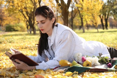 Photo of Woman reading book in park on autumn day