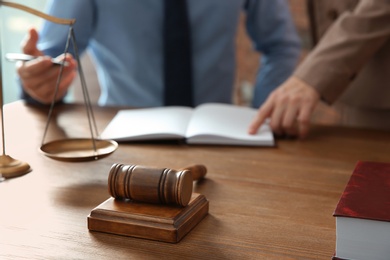 Photo of Notaries working at table in office, focus on judge gavel. Law and justice concept