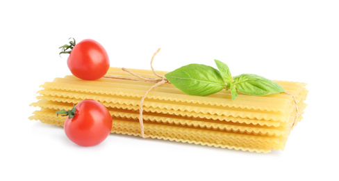 Photo of Uncooked lasagna sheets, cherry tomatoes and basil isolated on white