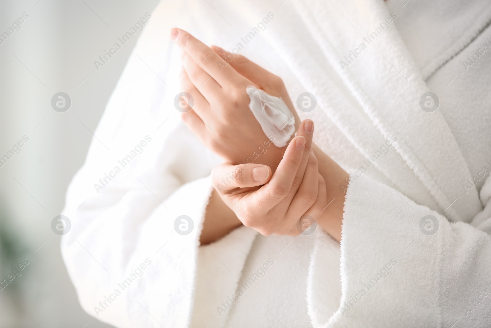 Photo of Young woman applying hand cream, closeup