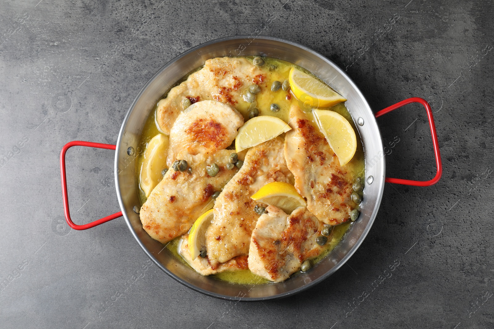 Photo of Delicious chicken piccata with lemons on grey table, top view