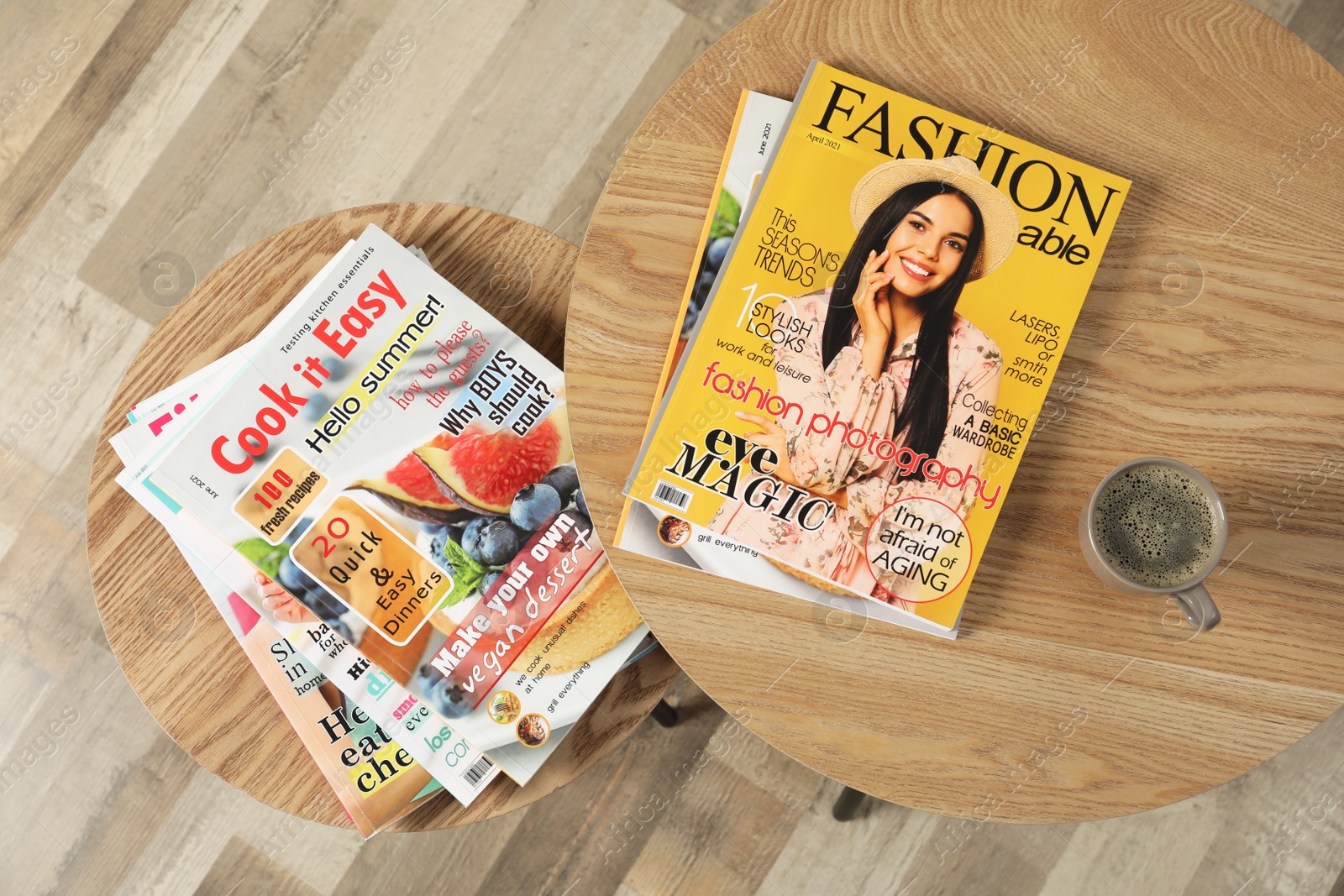 Photo of Wooden nesting tables with different magazines and cup of coffee indoors, top view