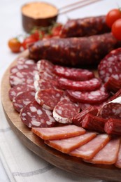 Photo of Different types of delicious sausages, sauce and tomatoes served on white table, closeup